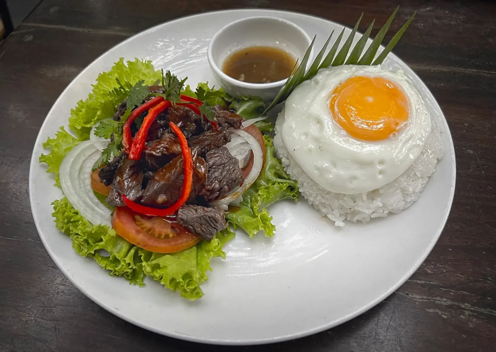 Lok Lak by Mr. Wanderer Lok Lak served on a bed of lettuce with rice and a fried egg.
