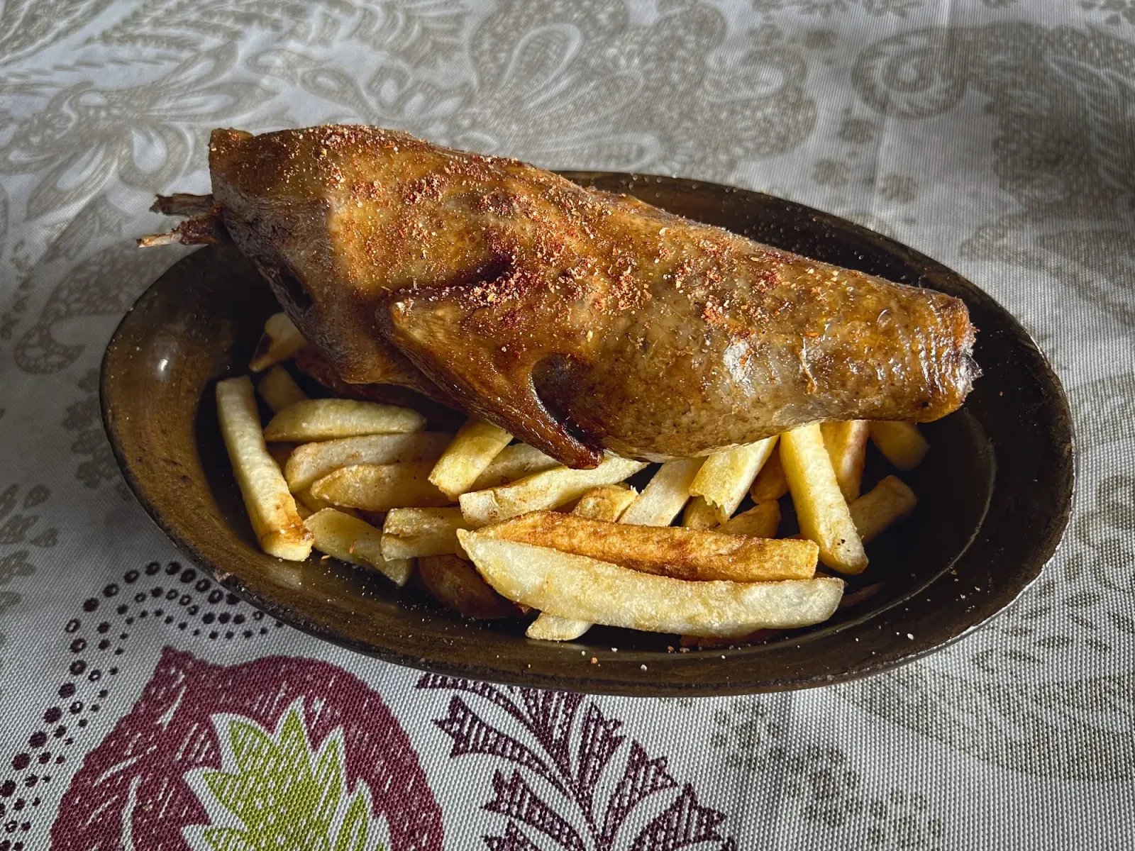 Stuffed Pigeon by Mr. Wanderer A whole stuffed pigeon lying on a bed of fries, table shot.