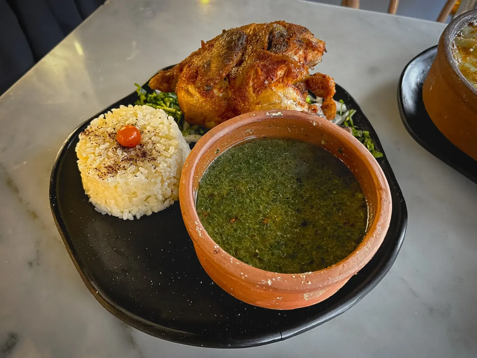 Molokhia by Mr. Wanderer Molokhia in a clay pot with a side of rice and chicken, angled shot.