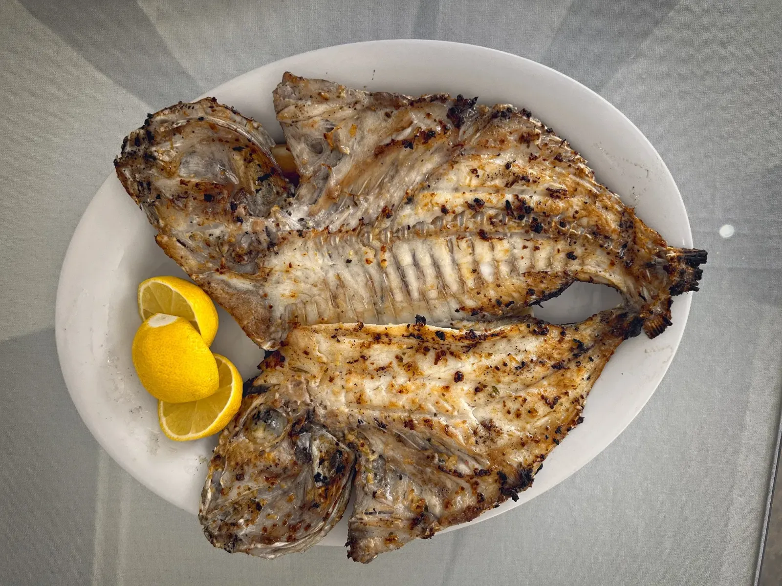 Samak Mashwi by Mr. Wanderer A whole fish split in half and opened up on the plate, overhead shot.