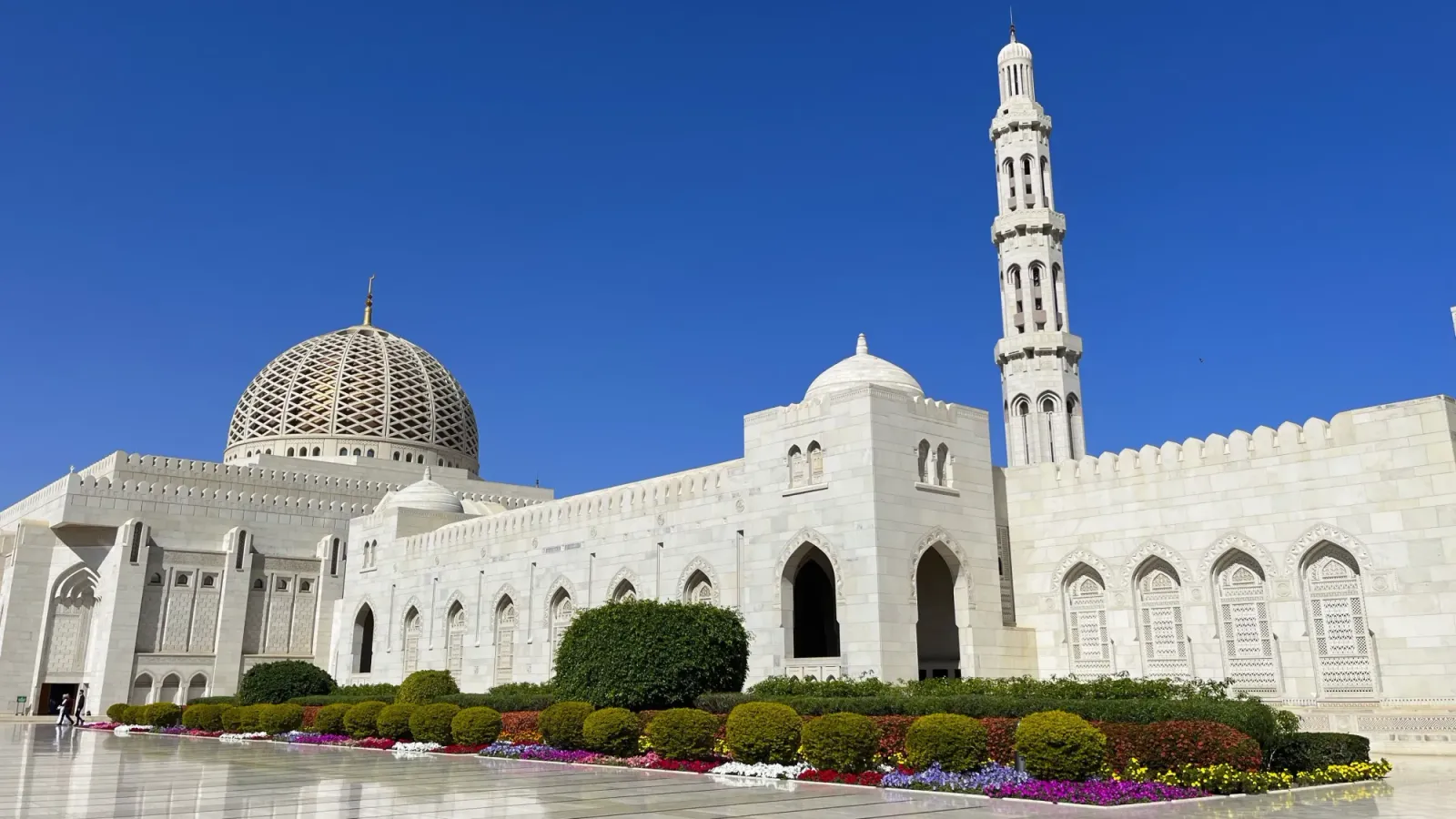 Sultan Qaboos Grand Mosque Exterior by Mr. Wanderer White exterior of the Sultan Qaboos Grand Mosque with a colorful flowerbed in front of it