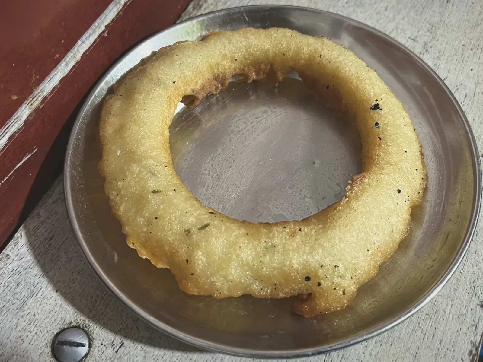 Sel Roti by Mr. Wanderer Close-up, angled shot of Sel Roti on a small silver plate.