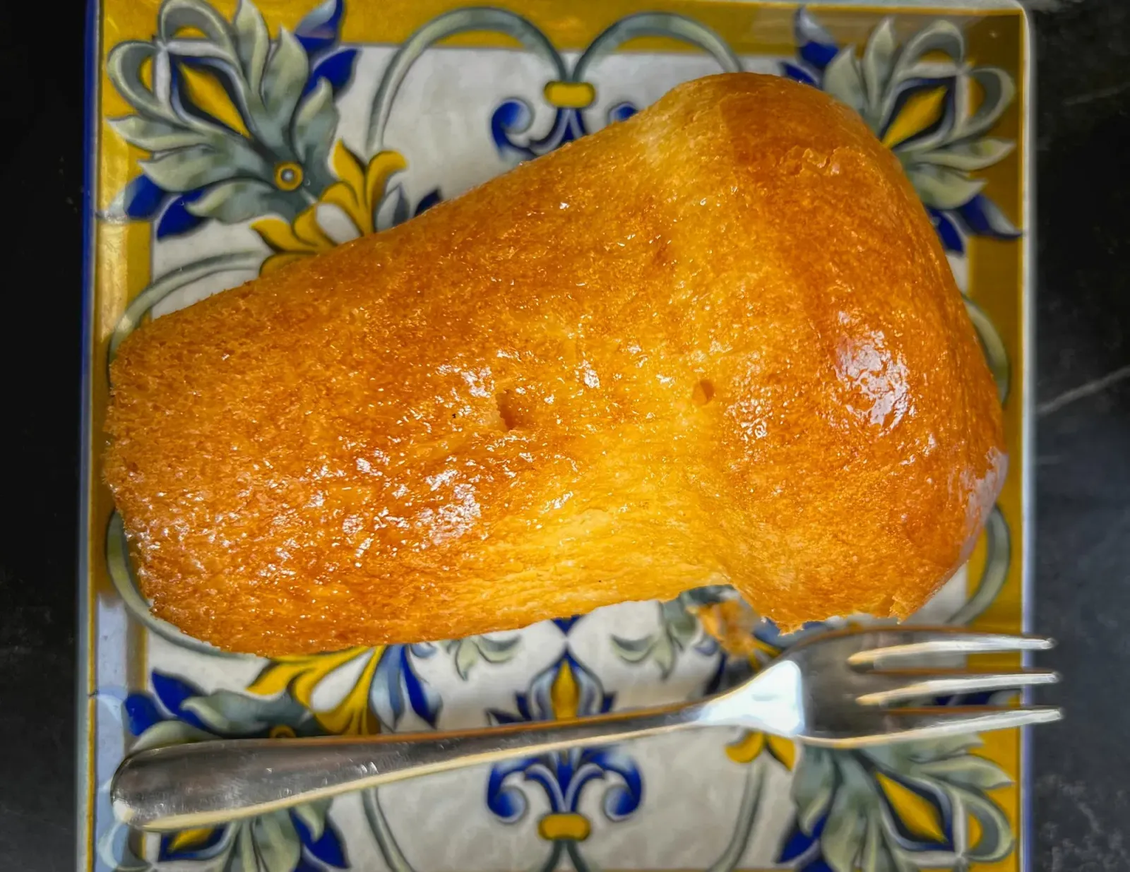 Babà by Mr. Wanderer Babà. Overhead shot on ornate plate with a fork.