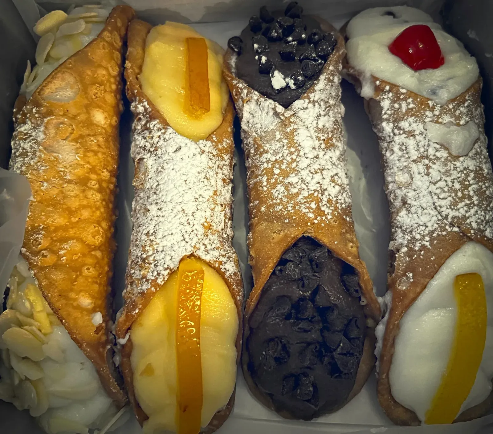 Canolli by Mr. Wanderer Canolli. Four canolli in a pastry box. Almond, orange, chocolate, and classic flavors.