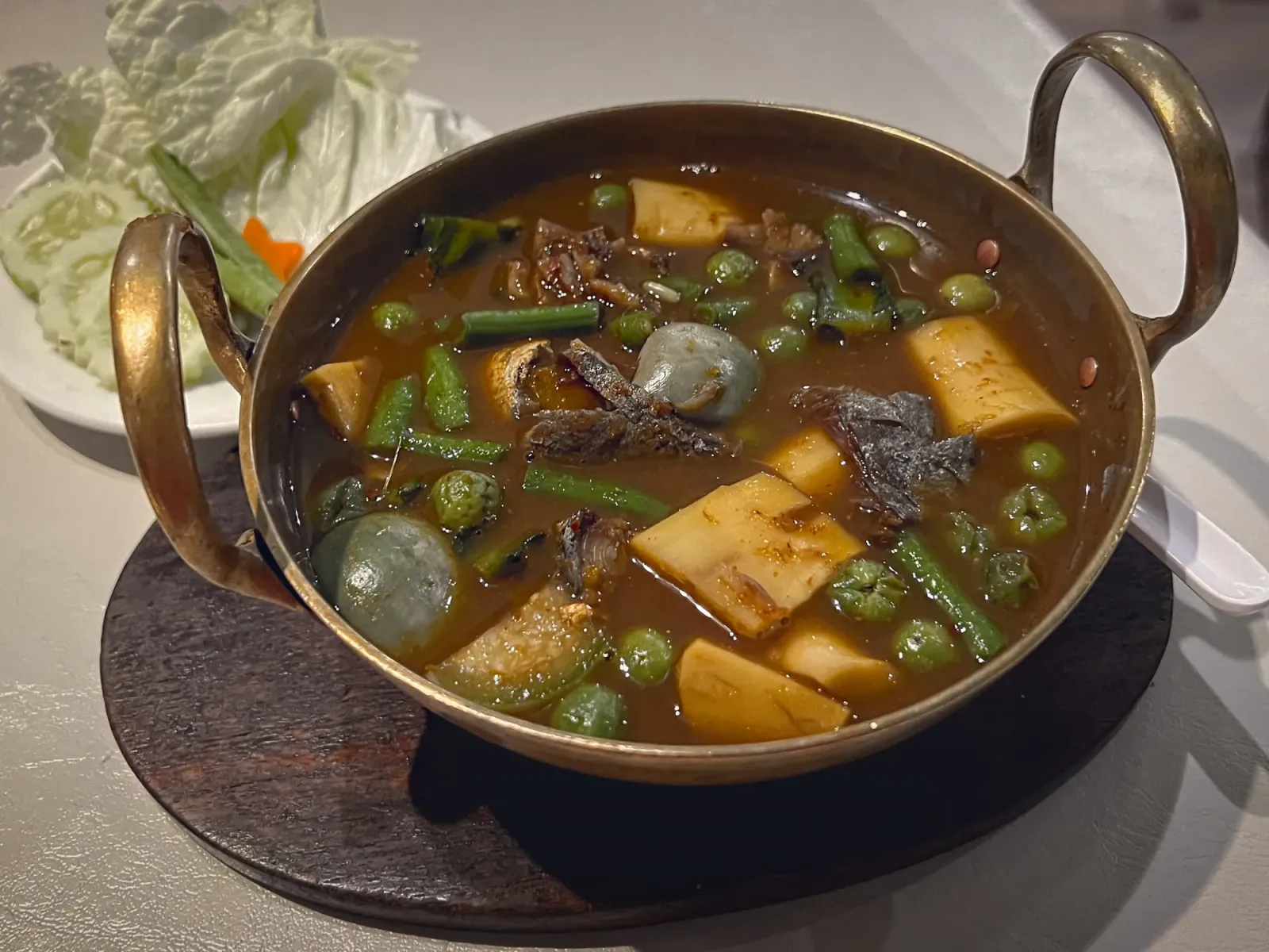 Kaeng Som by Mr. Wanderer Kaeng Som in a metal serving bowl, angled shot.