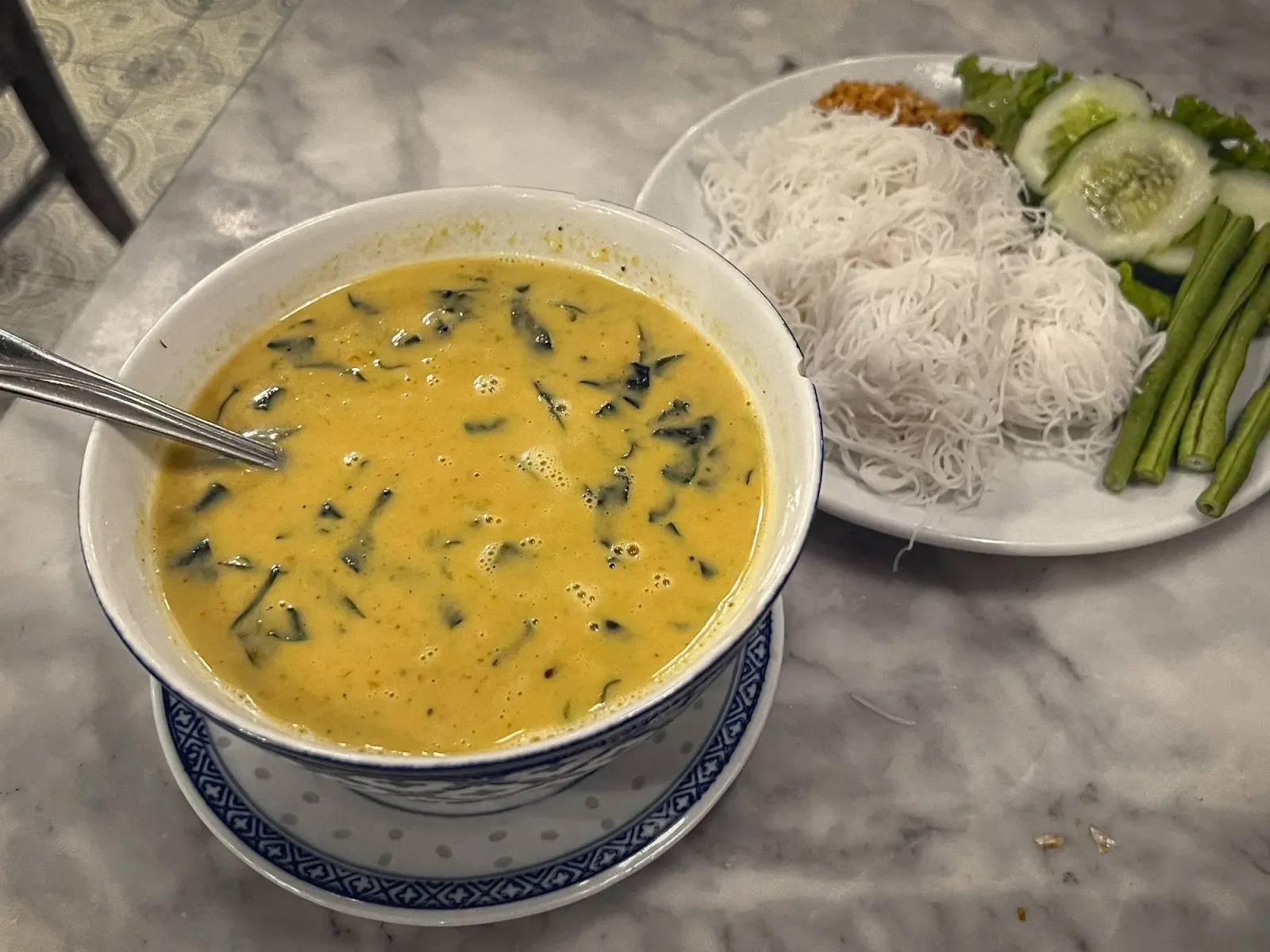 Sen Mee Gaeng Poo by Mr. Wanderer Sen Mee Gaeng Poo in a bowl with rice noodles and sides on a plate.