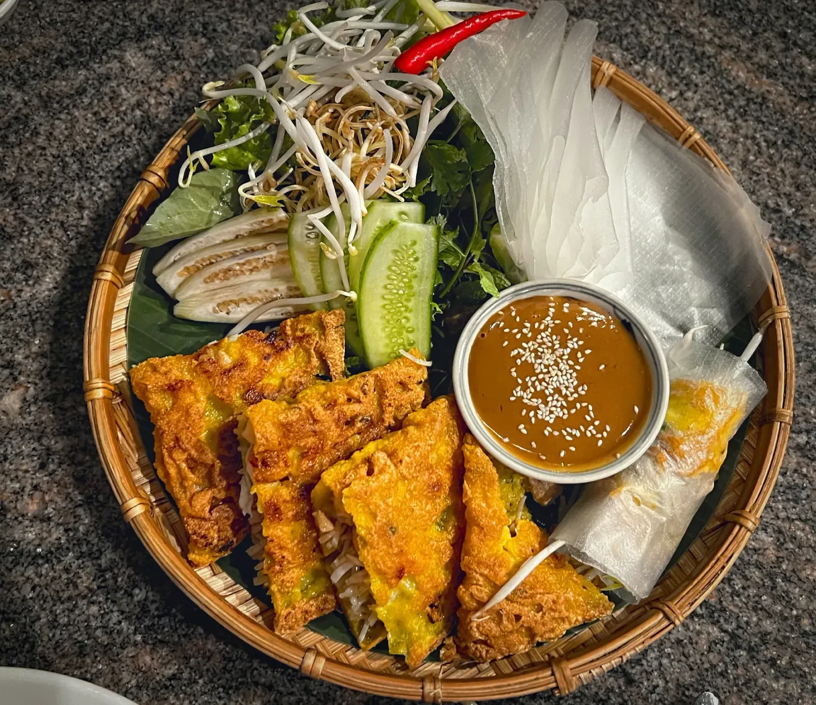 Bánh Xèo by Mr. Wanderer Bánh Xèo precut into 4 quarters with all fixings on a platter, overhead shot.