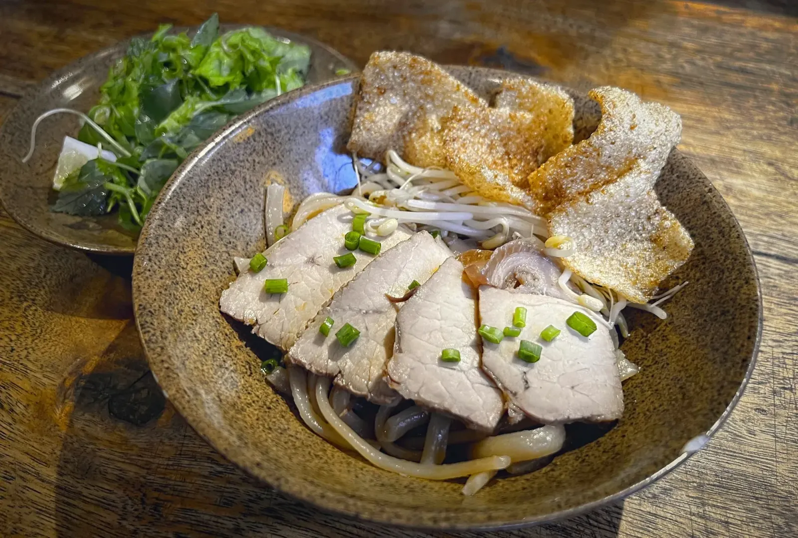 Cao Lầu by Mr. Wanderer Bowl of Cao Lầu with garnishes in background.