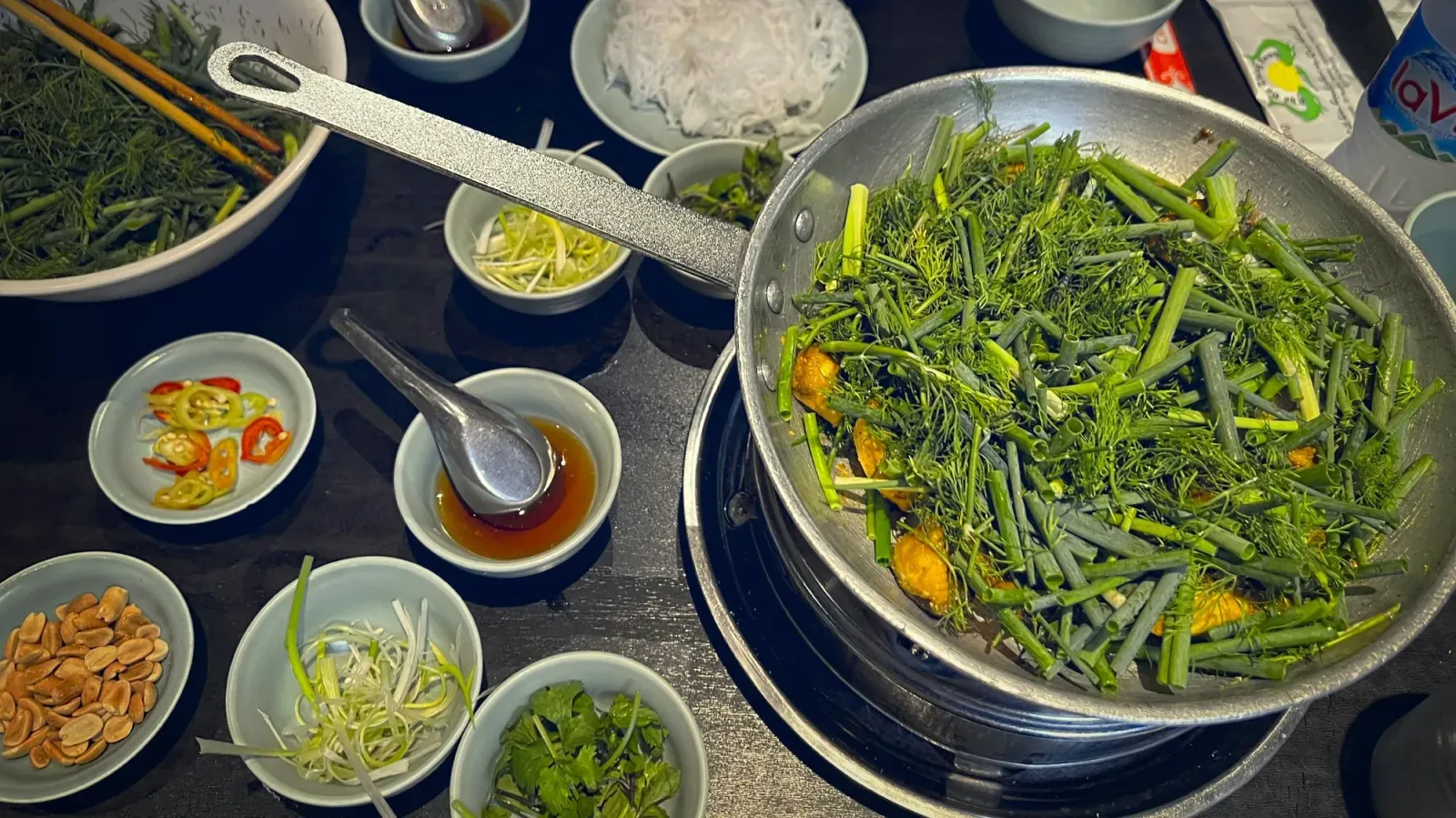 Chả cá by Mr. Wanderer Chả cá on the table. Cooked in a skillet on the table with many garnish dishes. Overhead shot.