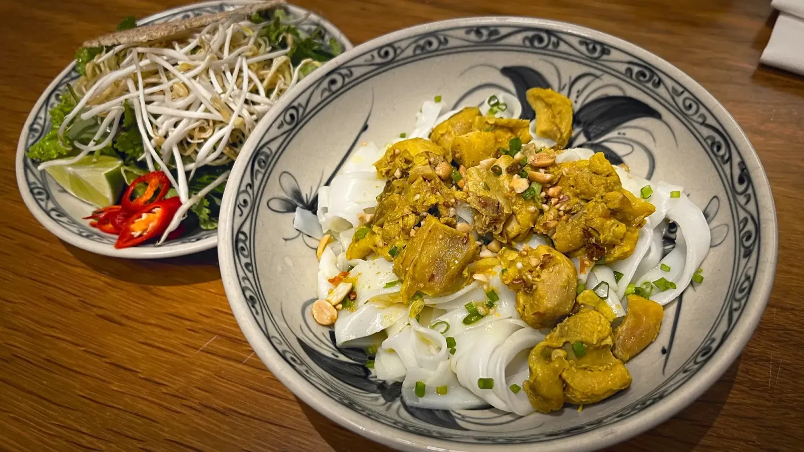 Mì Quảng by Mr. Wanderer Bowl of Mì Quảng with garnishes in background.