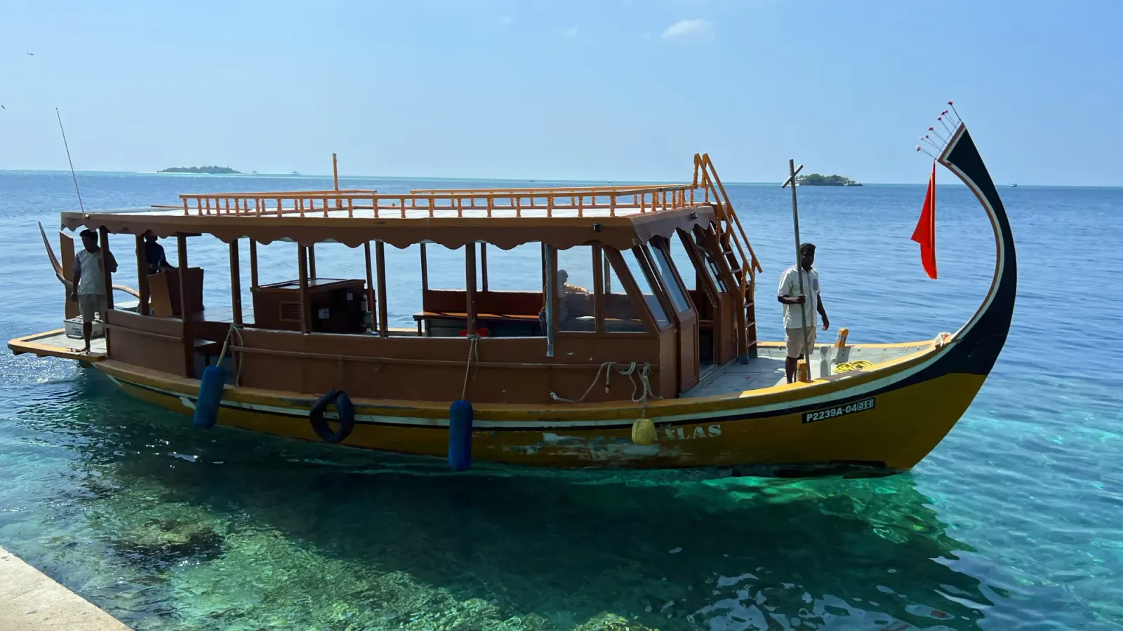 Maldivian Boat by Mr. Wanderer Boat with a curved hull and two men aboard
