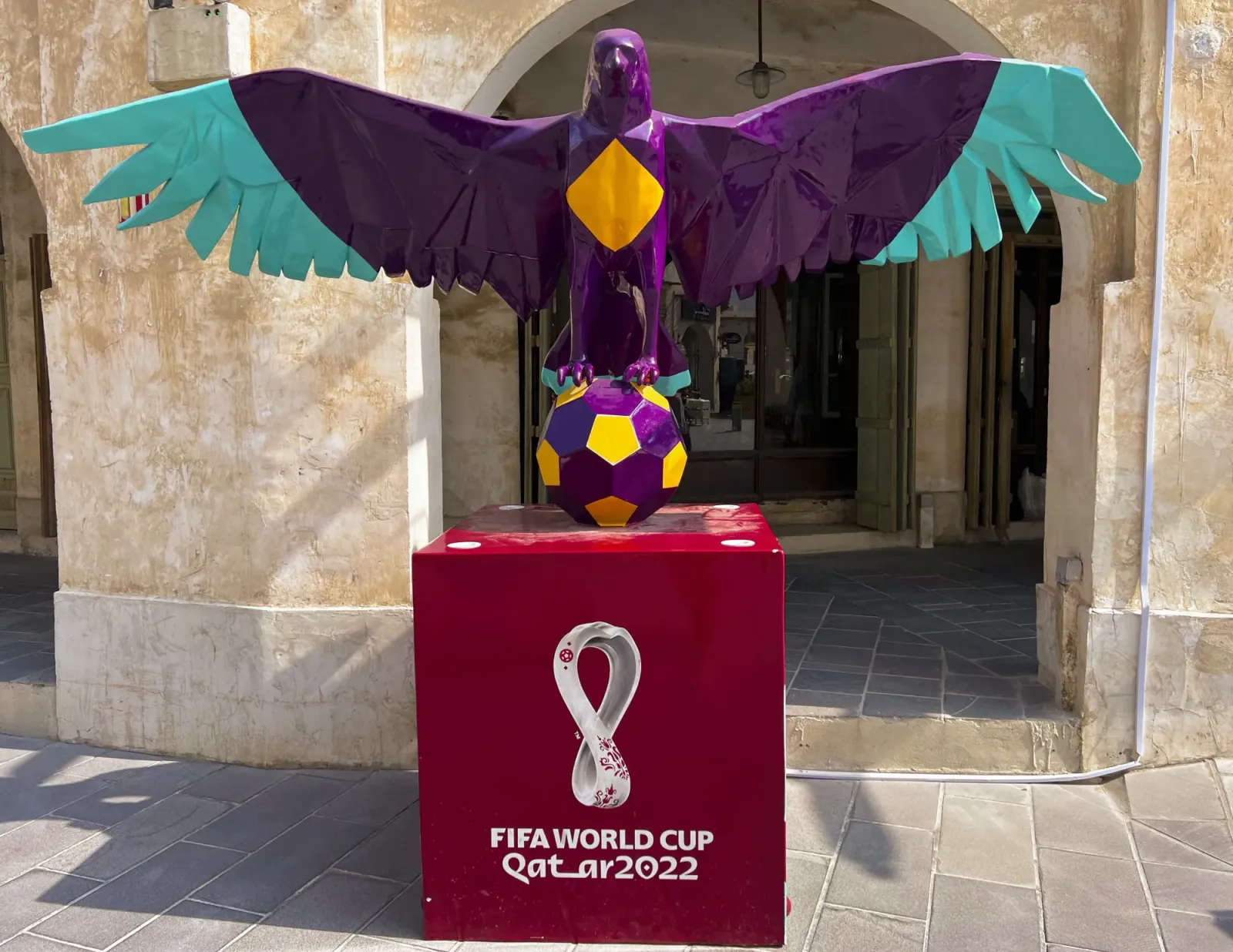 FIFA Paraphenalia by Mr. Wanderer A purple statue of a falcon perched on a soccer ball above a box for the 2022 FIFA World Cup