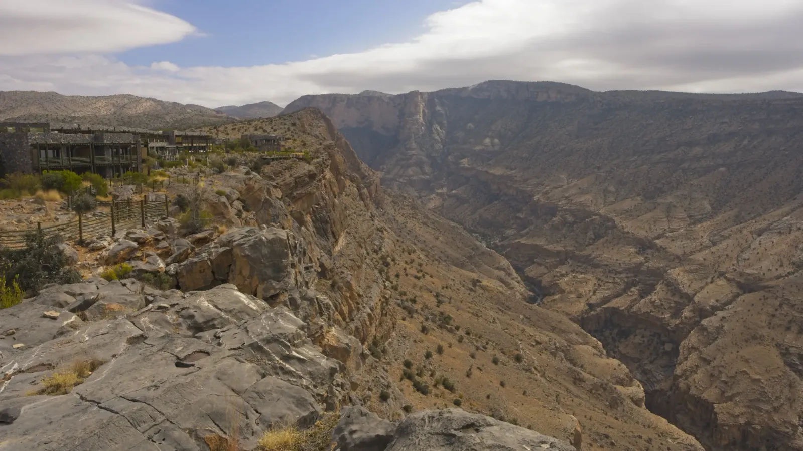 Resort Overlooking the Omani Grand Canyon by Mr. Wanderer Multicolored rock valley with the resort perched on the cliff's edge