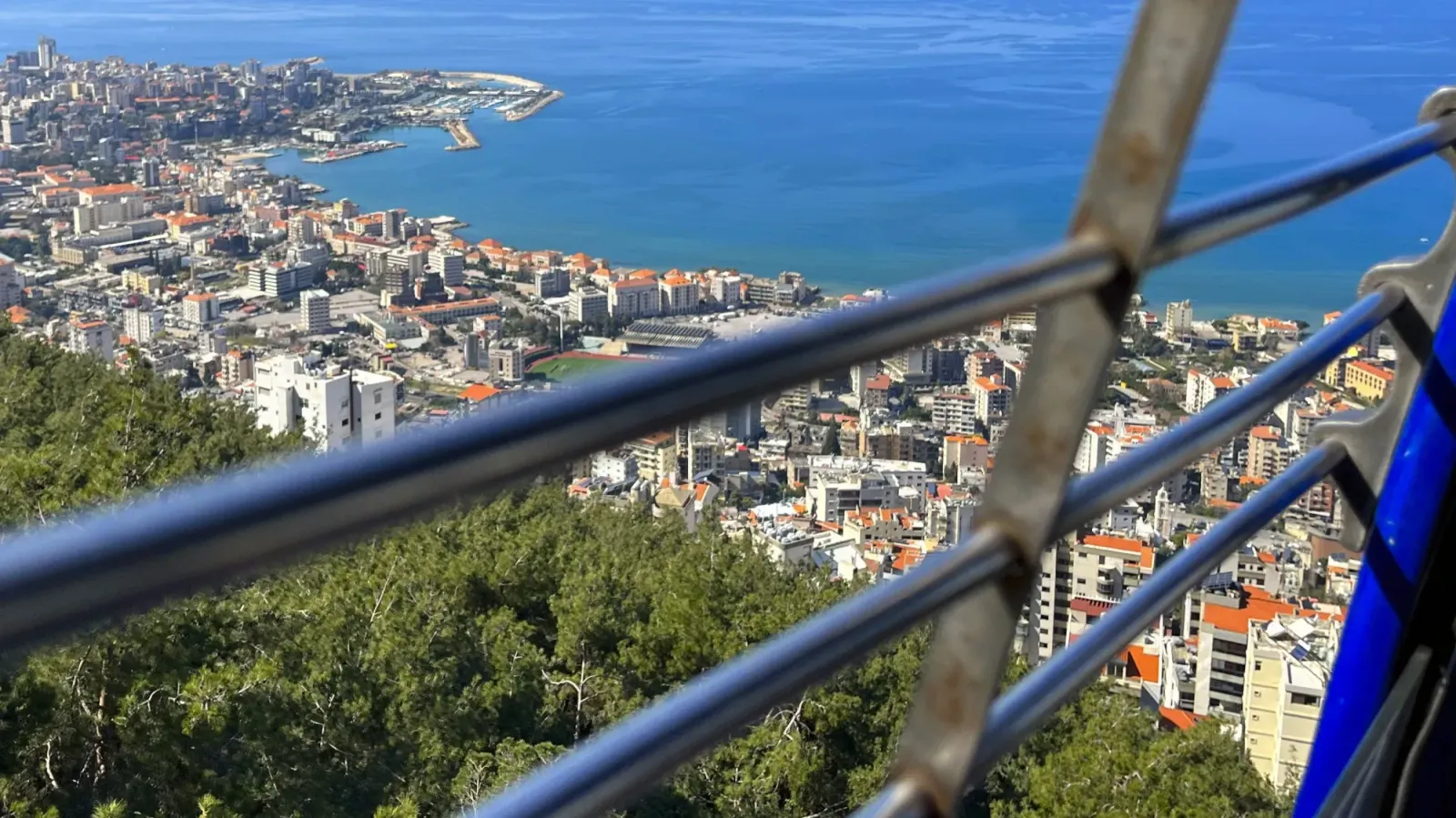 Harissa Cable Car by Mrs. Wanderer View through the bars in a cable car overlooking the city with orange roofs