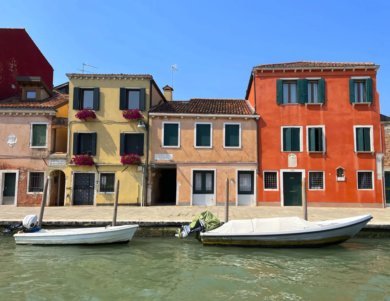 Burano Buildings by Mrs. Wanderer Pastel home fronts with two white boats moored in the water