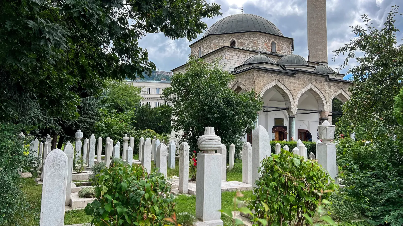 Gazi Husrev-beg Mosque by Mr. Wanderer White brick mosque with skinny marble headstones