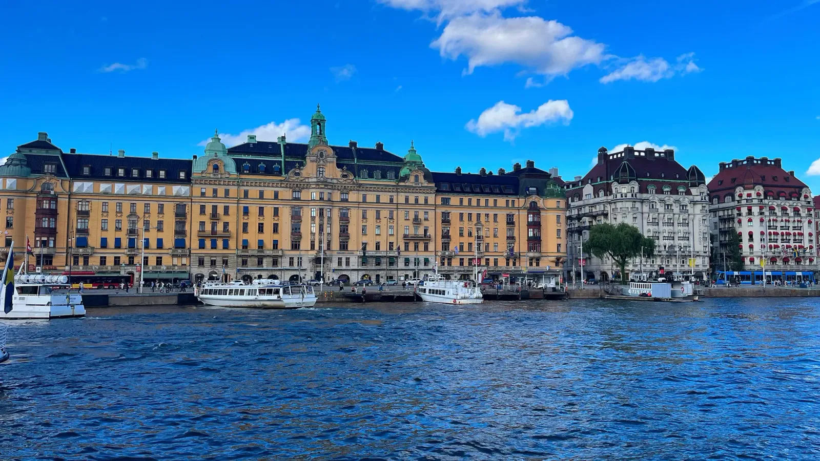 Ladugårdslandsviken by Mrs. Wanderer Blue harbor water with yellow Swedish building and white boats