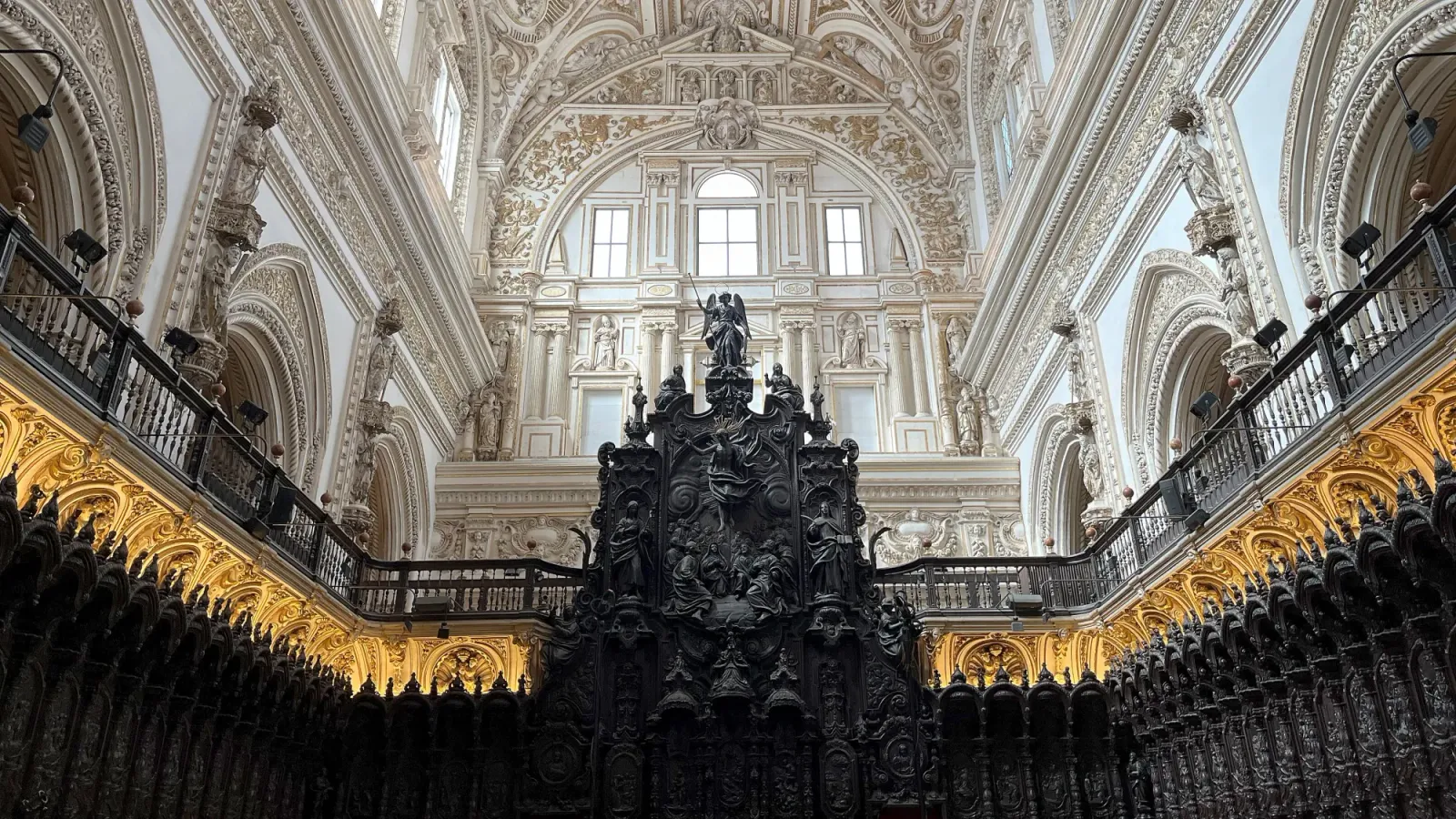 Mezquita Quire by Mrs. Wanderer Black wooded seating with ornate white ceiling