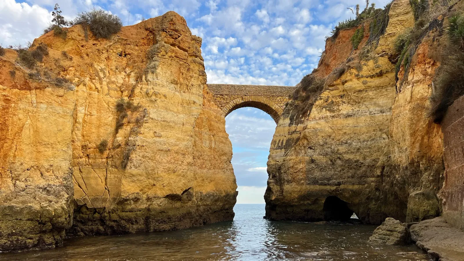 Lagos Archway by Mrs. Wanderer Rocks coming out of the water with a stone bridge between them