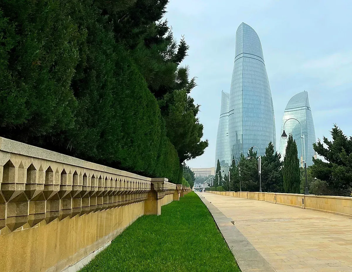 Flame Towers by Mr. Wanderer Stone walkway lined with trees pointed at three glass skyscrapers