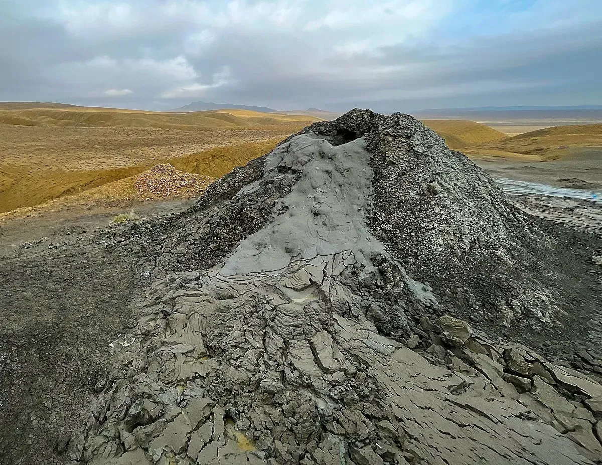 Mud Volcano by Mrs. Wanderer Grey mound of coagulated grey mud billowing out of the top of the volcano