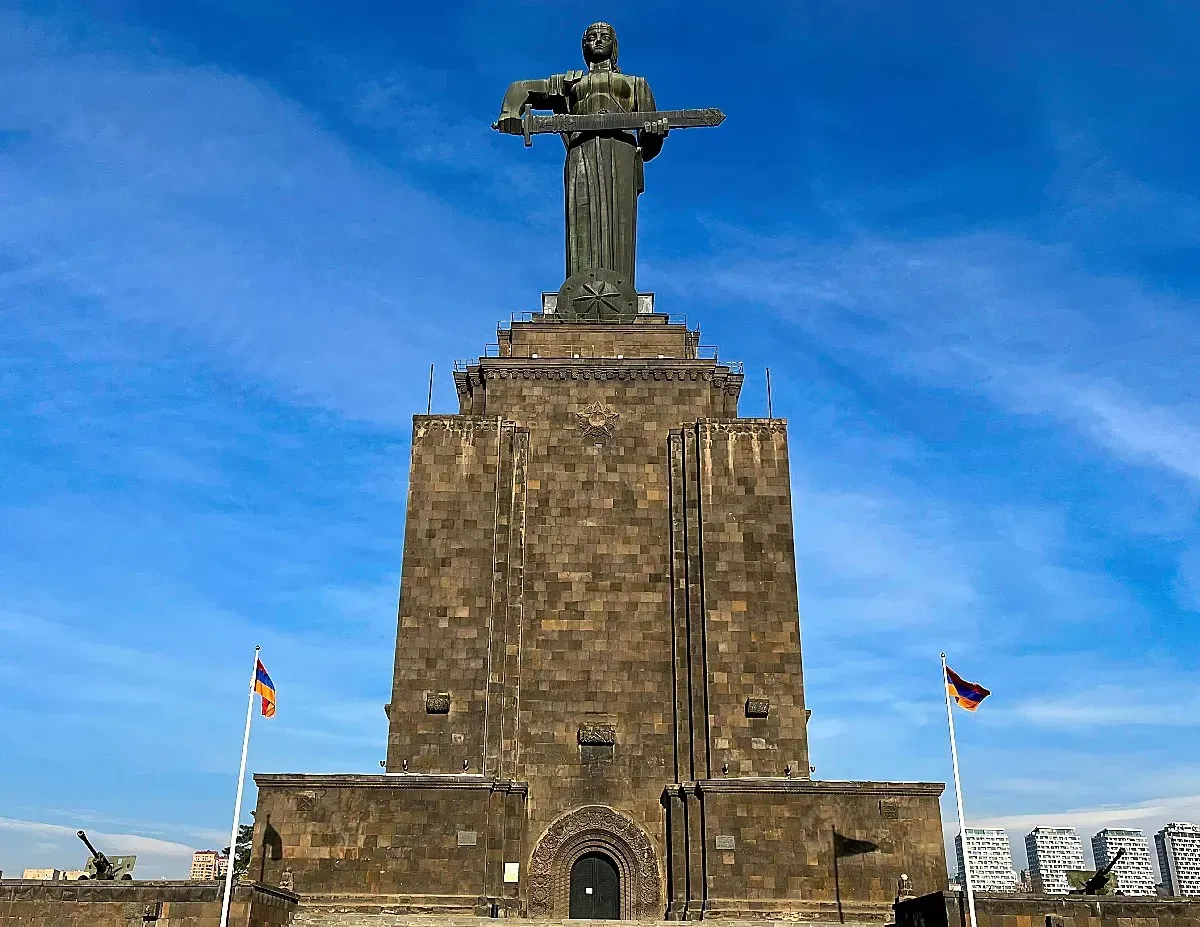 Mother Armenia by Mr. Wanderer Female Statue holding a sword flanked by two Armenian flags