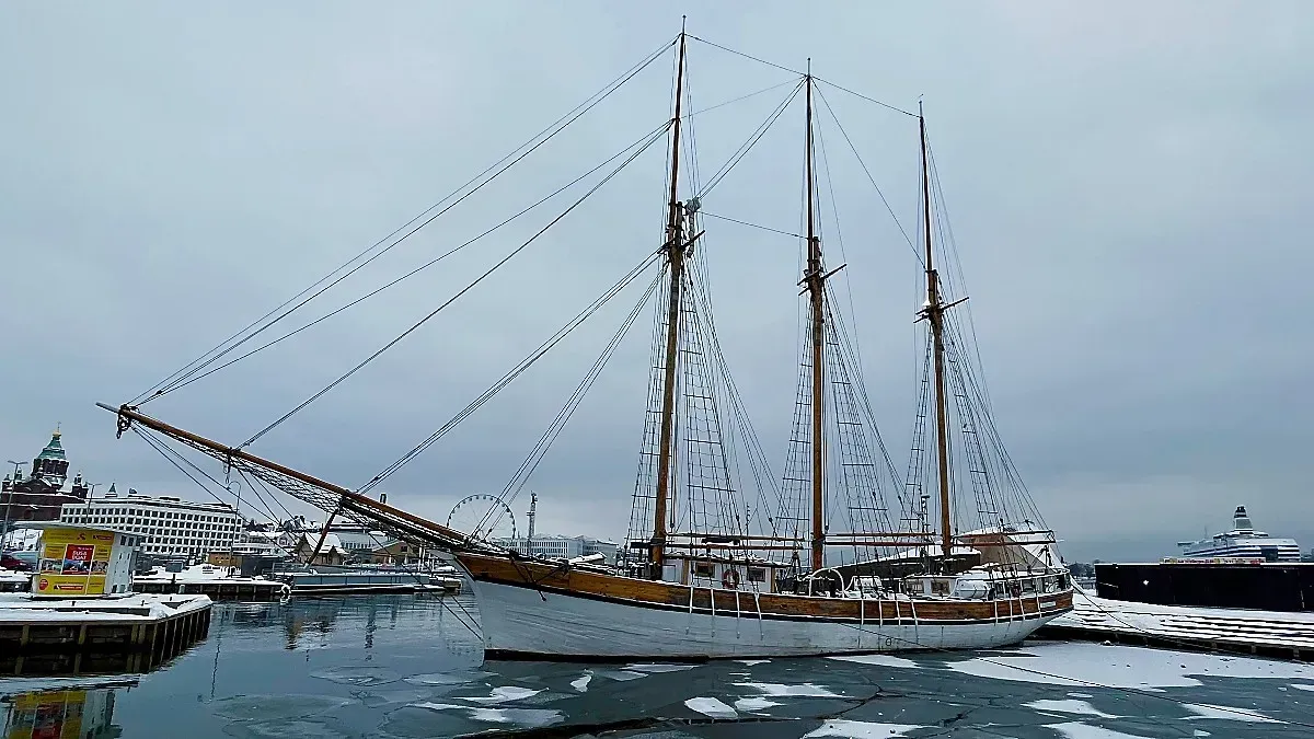 Helsinki Winter Harbor by Mr. Wanderer Wooden boat, painted white, floating over sheets of ice in a cloudy harbor