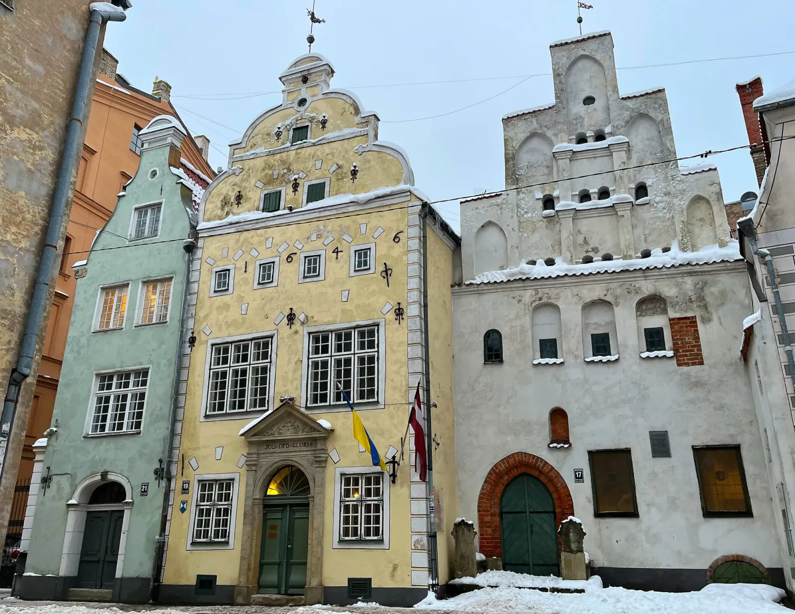 Three Brothers by Mr. Wanderer Old green, yellow, and white building faces