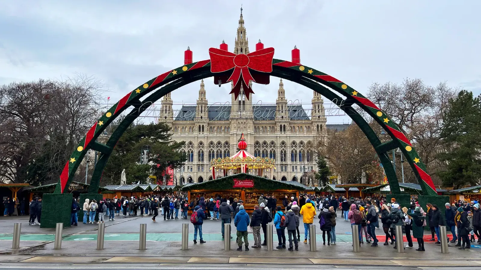 Vienna Christmas Market by Mr. Wanderer Green and red ribboned archway before a village of huts set in front of an ornate building