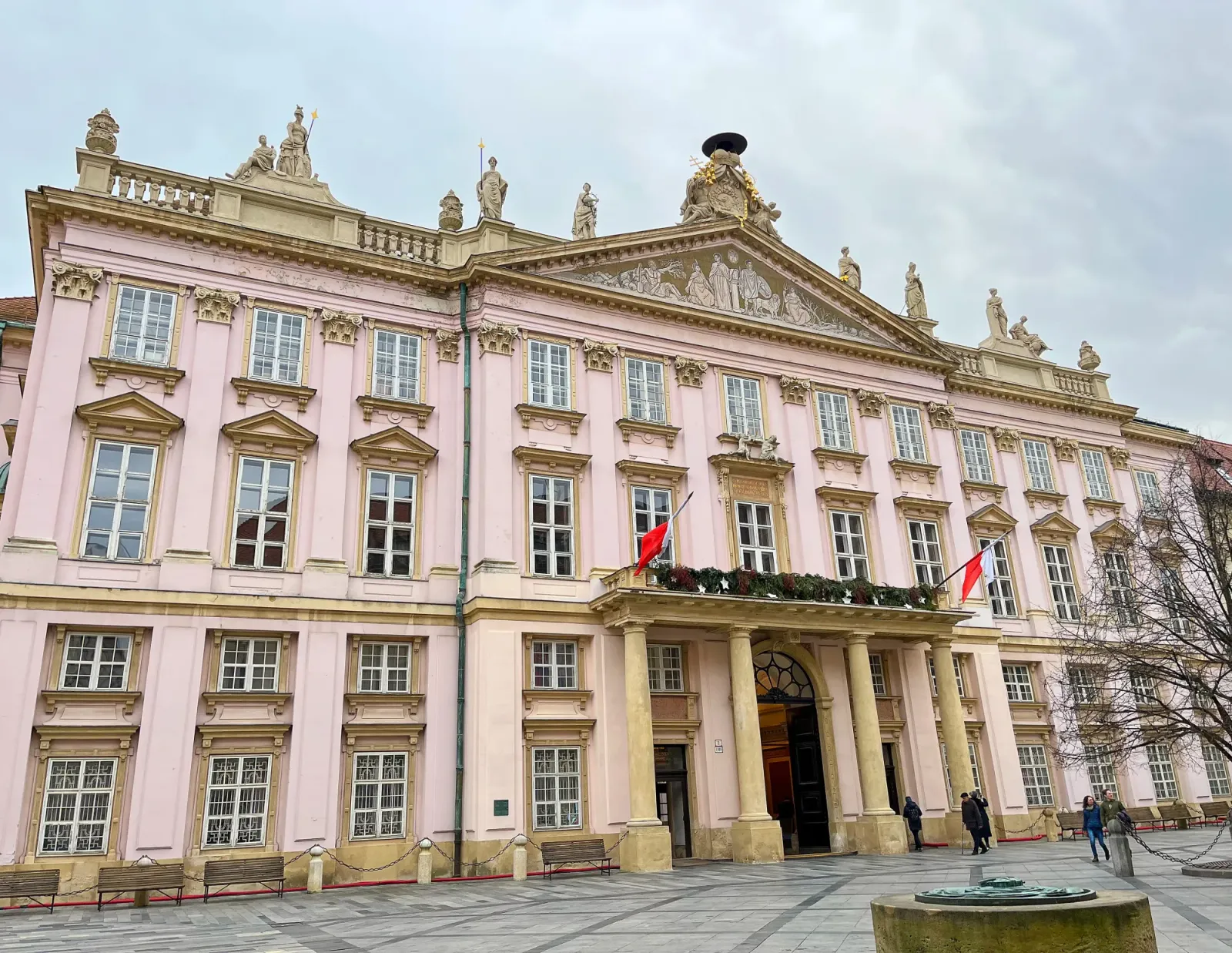 Primacial Palace by Mrs. Wanderer Ornate pink building with tan stone columns and statues