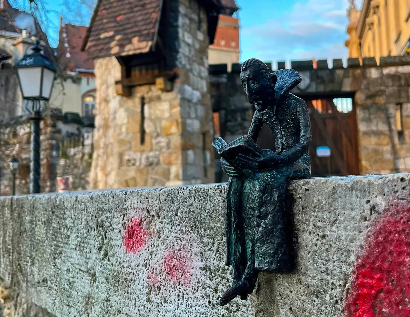 Dracula Reading by Mrs. Wanderer Black statue of Dracula reading a book while sitting on a ledge