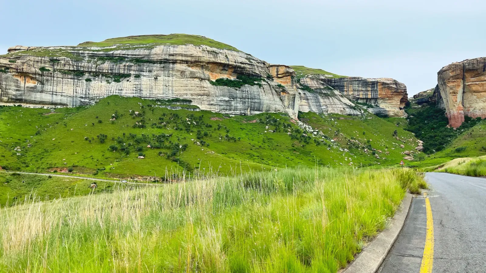 Golden Gate Highlands National Park by Mr. Wanderer Striped rock face jutting out from green grasses along the roadway