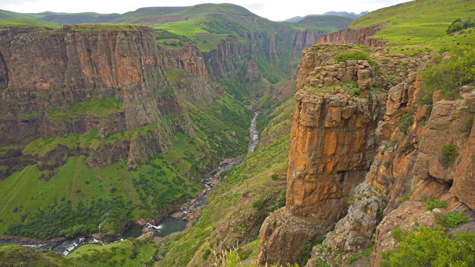 Lesotho Valley by Mr. Wanderer Valley with green grasses and a river running through it