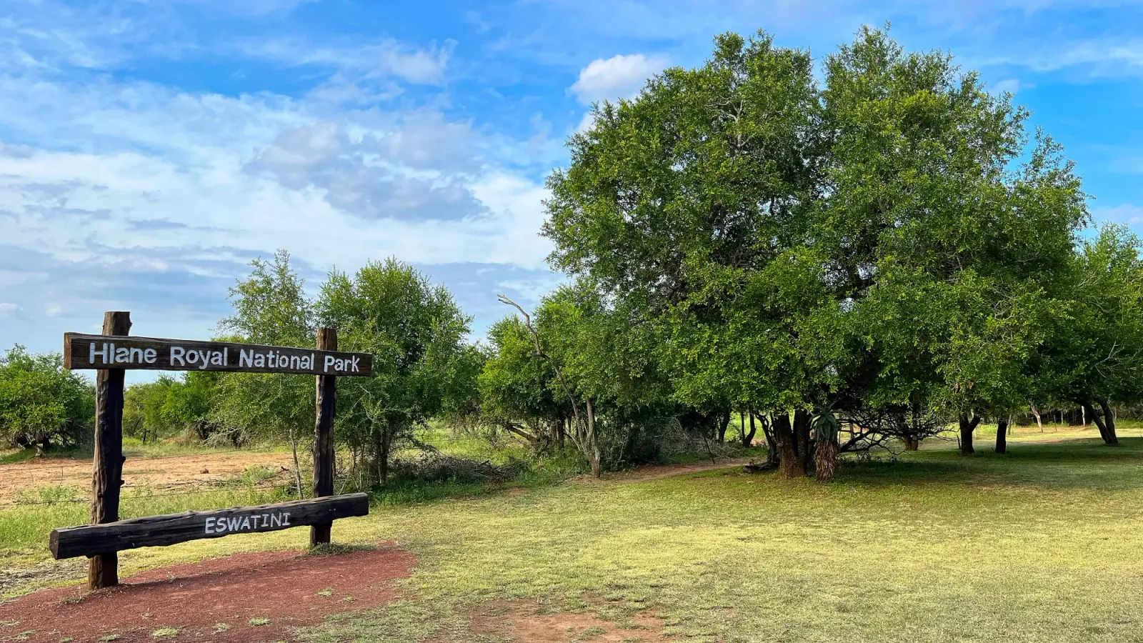 Hlane Royal National Park by Mrs. Wanderer Wooden frame naming the park in front of grass and a large tree