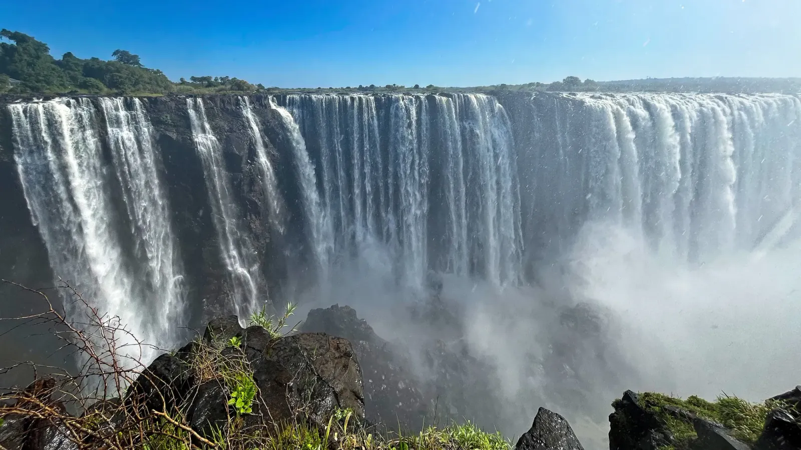 Victoria Falls by Mr. Wanderer Wide angle of water pouring off the side of the rocks into the misty abyss