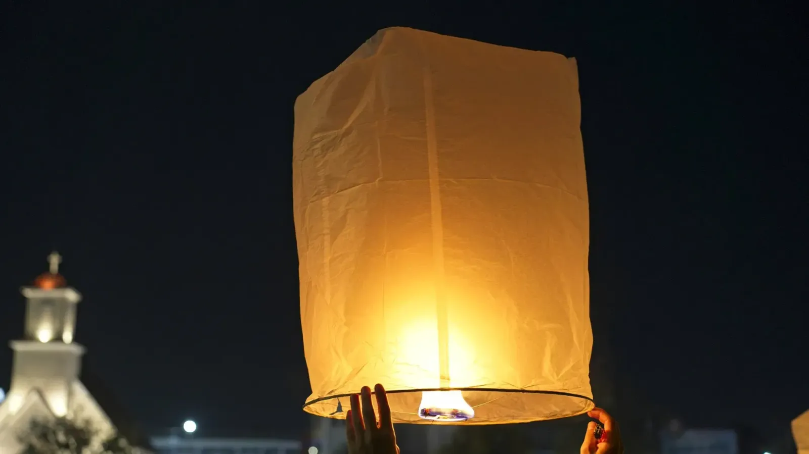 Chiang Mai Floating Lantern by Mr. Wanderer Close up image of hands holding a lit floating lantern