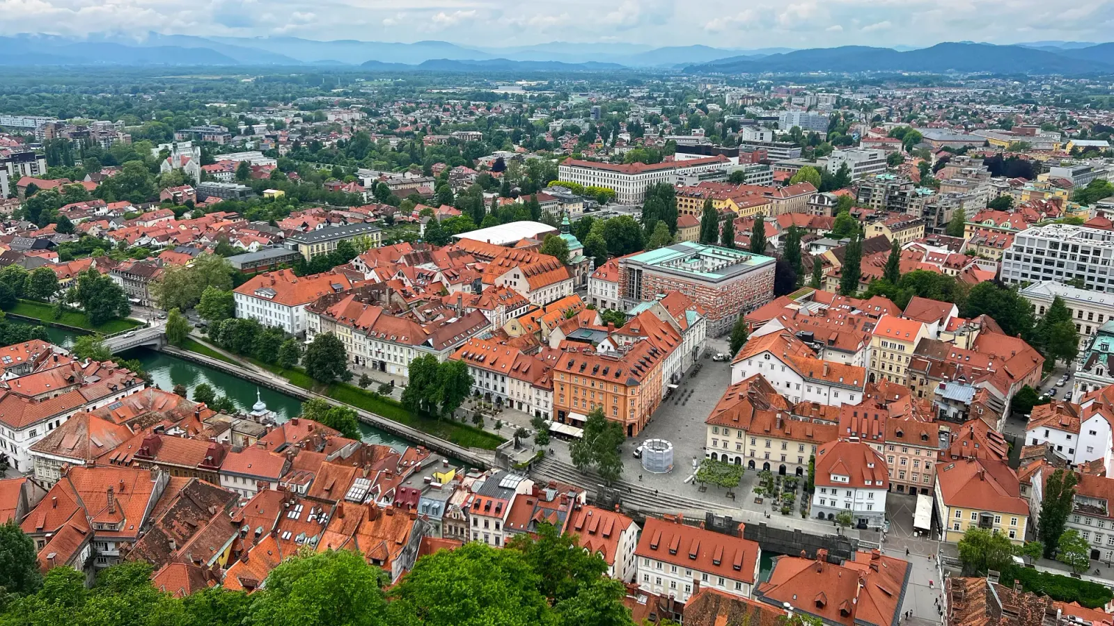 Ljubljana Cityscape by Mrs. Wanderer Birds-eye view of the orange roofs of the city interspersed with many lush trees