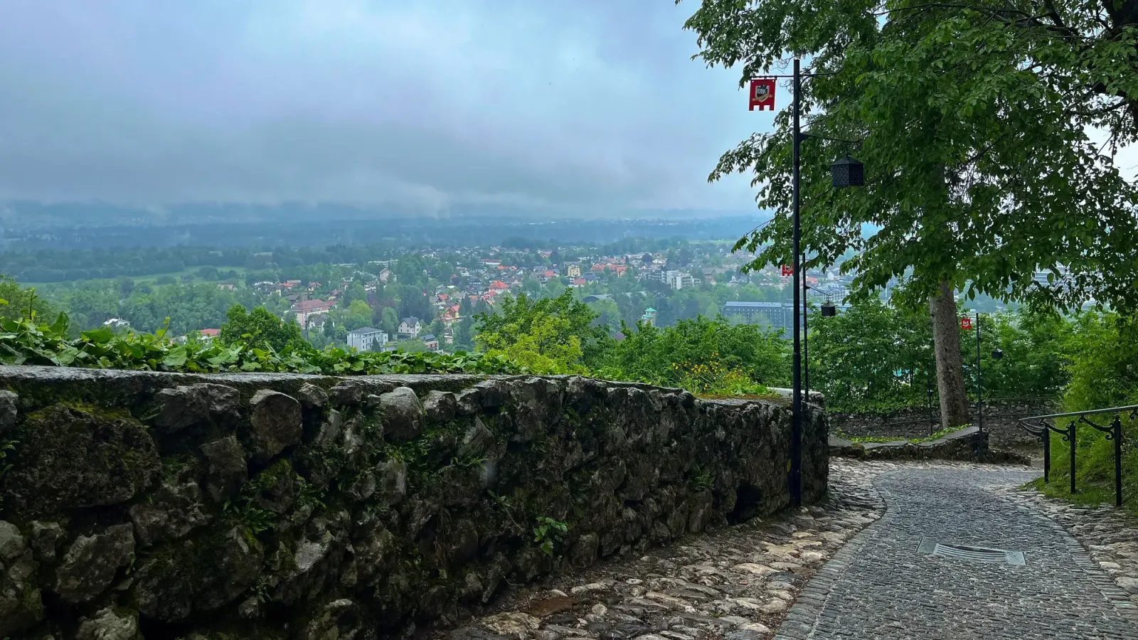 Bled Walkway by Mrs. Wanderer Slanted stone path between greenery under a misty sky