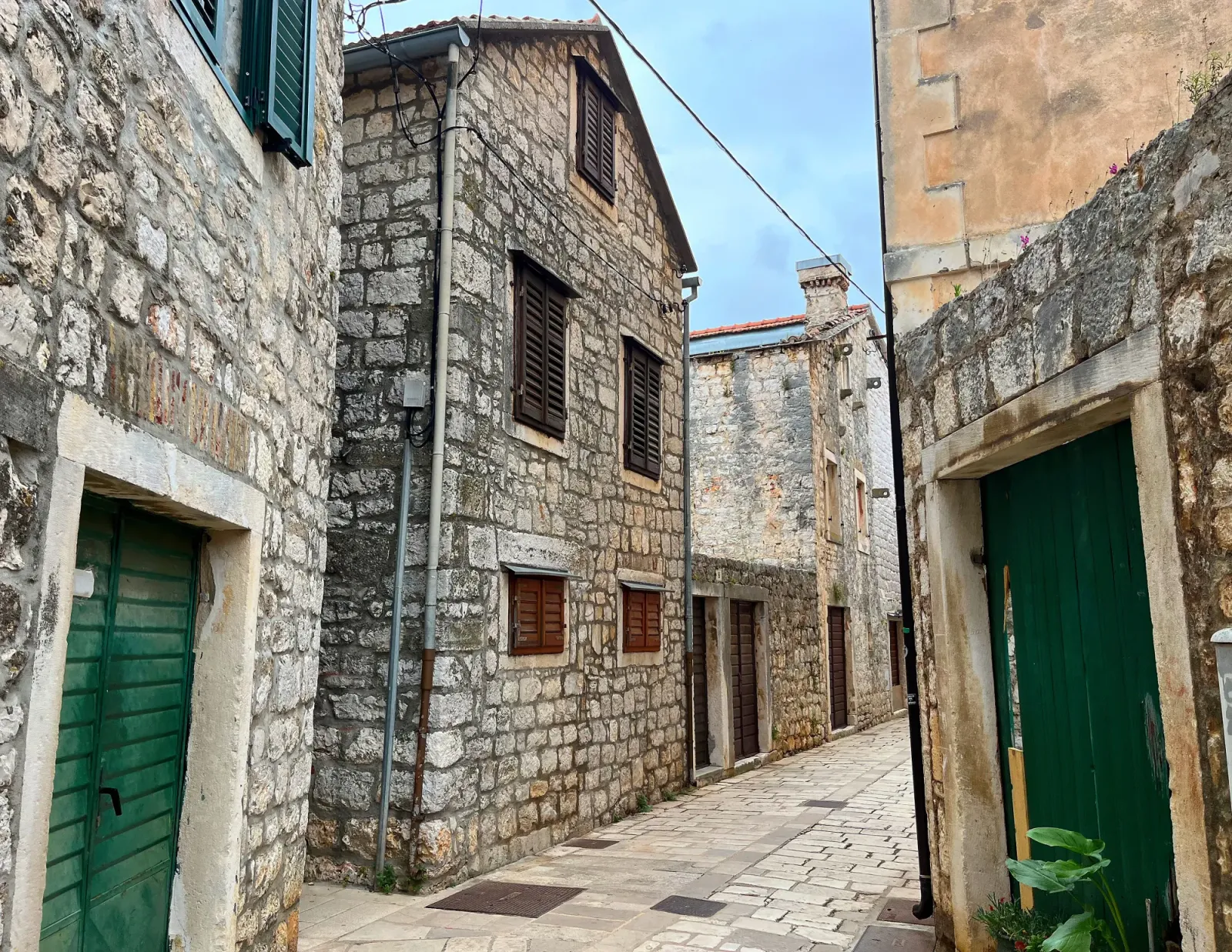 Stari Grad Street by Mrs. Wanderer Grey stone street and buildings with green shuttered doors