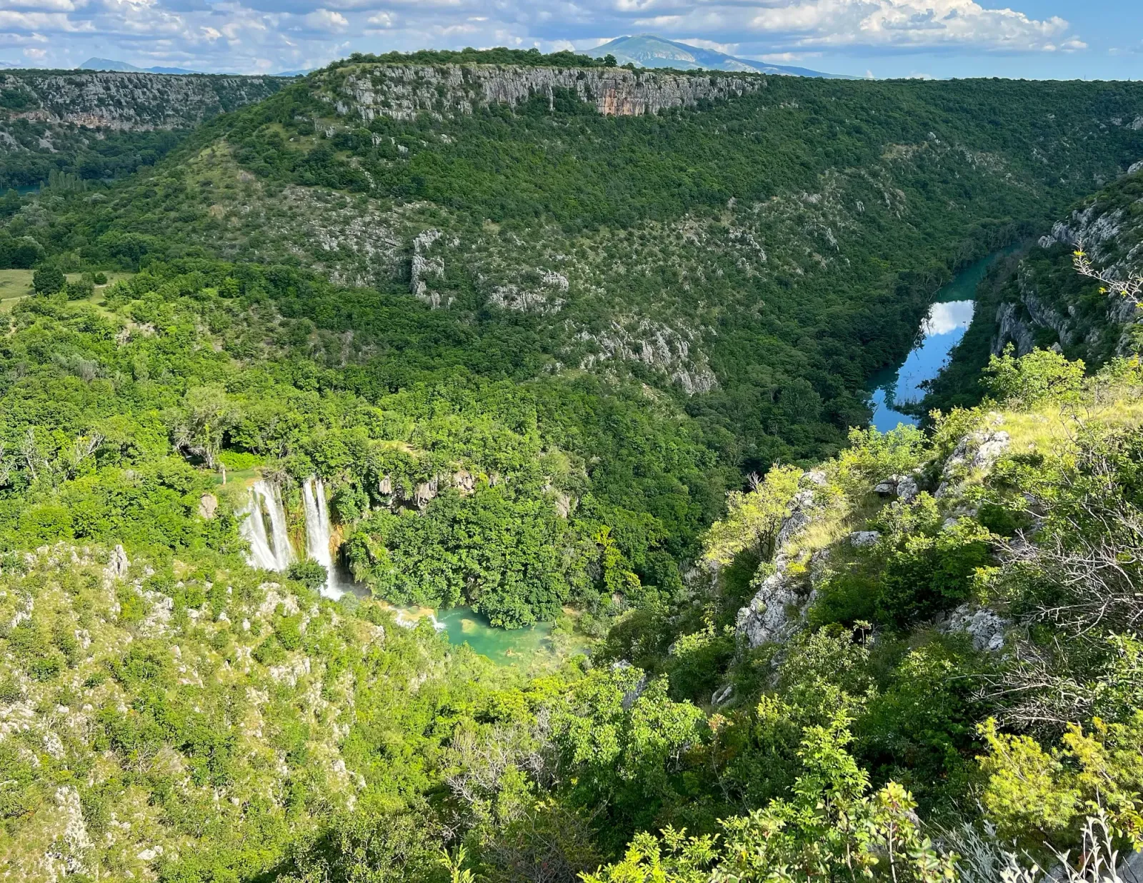 Manojlovac Waterfall by Mrs. Wanderer Green valley with a waterfall and reflective lake