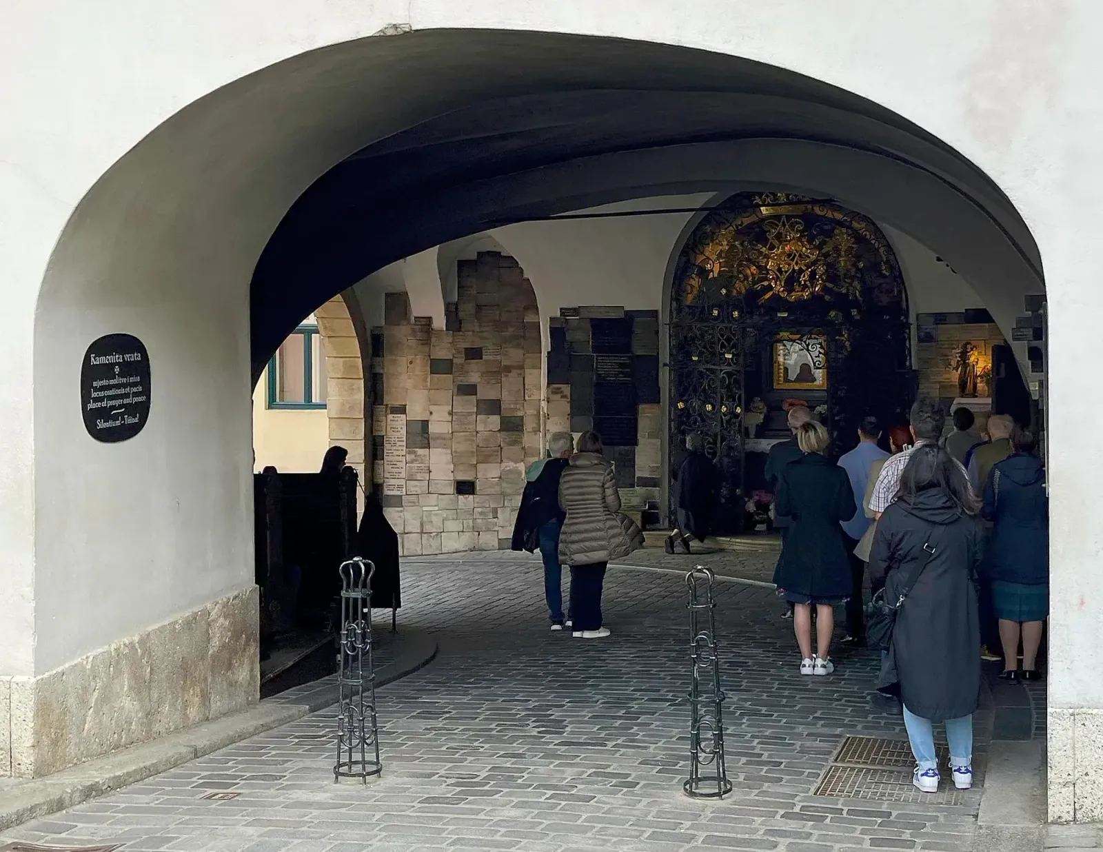 The Stone Gate by Mrs. Wanderer Arch-covered curved pathway with an ornate altar and a small crowd all standing in front of it