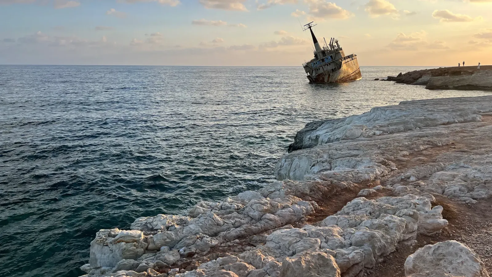 Rocky landscape seaside with a beached tilted cargo ship at sunset