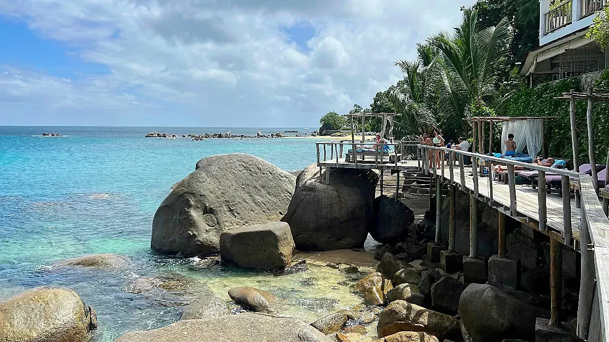 Seychelles Afternoons by Mr. Wanderer Large boulders bolster a wooden deck with sun beds overlooking the ocean