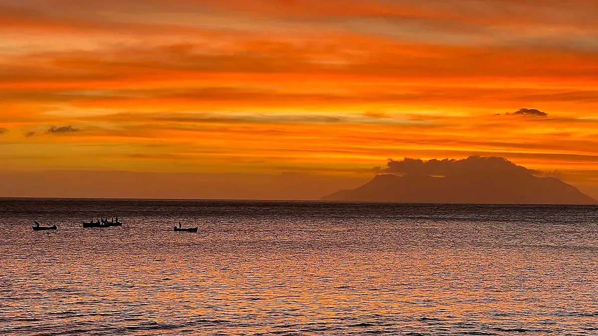 Seychelles Sunset Sailors by Mr. Wanderer Very orange sky with silhouettes of boys on row boats in the water